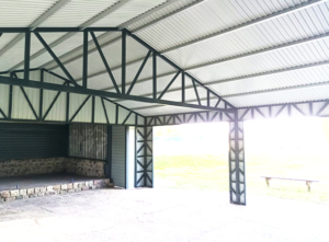 7x7m DELUX carport / tractor shed with gable roof, skirting, horizontal sheeting on the posts and vertical sheeting under the roof, double painted (black) frame structure