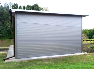 6,3x5,3m-es DELUX szigetelt mobilgarázs hátra lejtő tetővel, szekcionált kapuval, ajtóval, ablakokkal, szegélyekkel, ereszcsatornával, horganyzott vázszerkezettel