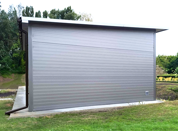 PULION DELUX minőségi szendvicspanel garázs YUKON 6,3x5,3m-es DELUX szigetelt mobilgarázs hátra lejtő tetővel, szekcionált kapuval, ajtóval, ablakokkal, szegélyekkel, ereszcsatornával, horganyzott vázszerkezettel