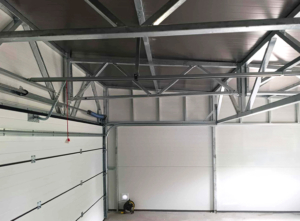 6,3x5,3m-es DELUX szigetelt mobilgarázs hátra lejtő tetővel, szekcionált kapuval, ajtóval, ablakokkal, szegélyekkel, ereszcsatornával, horganyzott vázszerkezettel